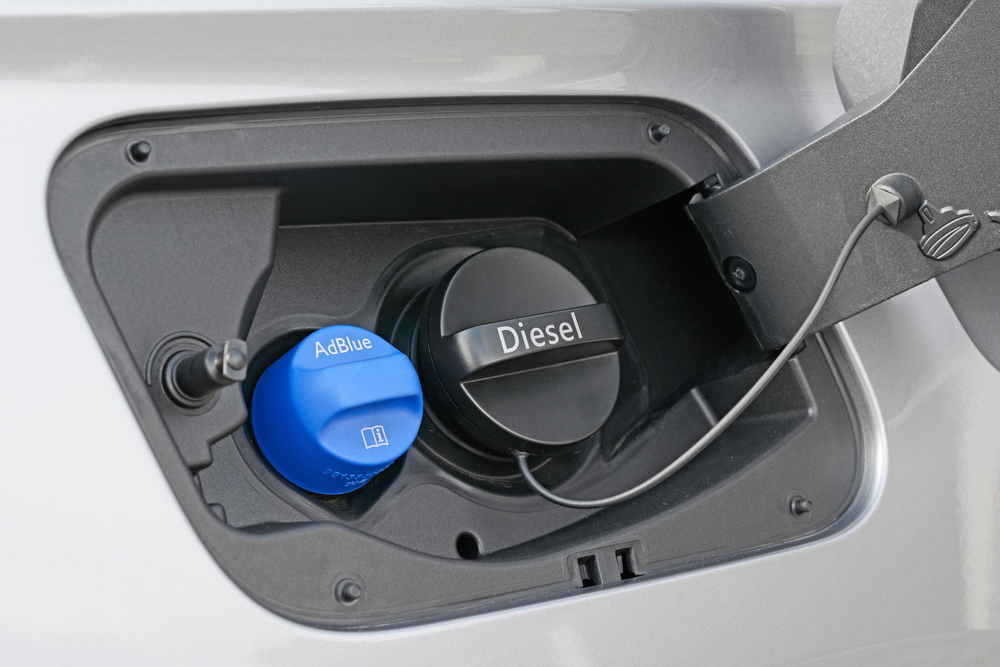 Blue AdBlue filler cap next to the diesel cap inside the fuel flap of a European diesel car